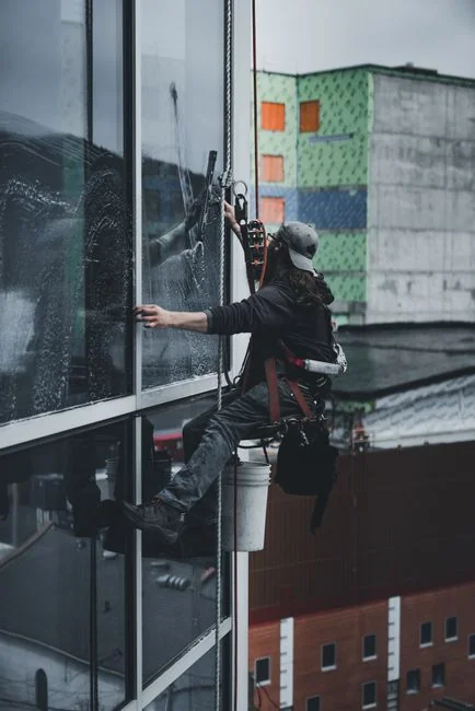 An adult male cleaning a glass window indoors, focusing on household chores and cleanliness.